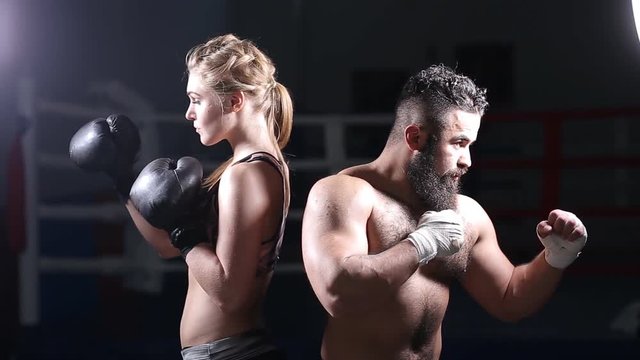 Sportswoman on sparring with her kickboxing instructor. Man and a woman in the Boxing ring