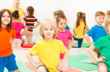 Big group of happy kids kneeling during gymnastics