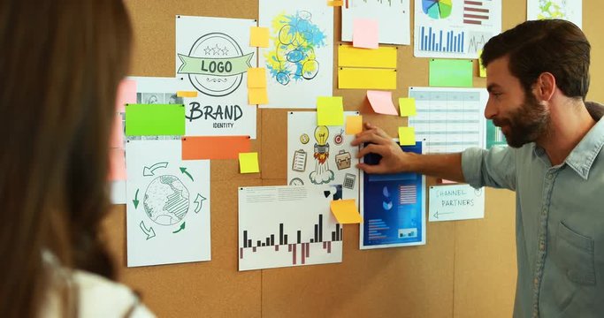 Business colleagues discussing over bulletin board