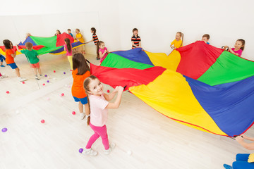 Happy girl playing parachute game with her friends