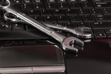 wrench tool and screwdrivers over a laptop