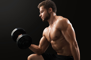 Fototapeta na wymiar Muscular ripped young man doing biceps exercise lifting dumbbells on black background gym sport athlete determination energy strength power lifestyle gym fitness sexy arms weightlifting bodybuilding.