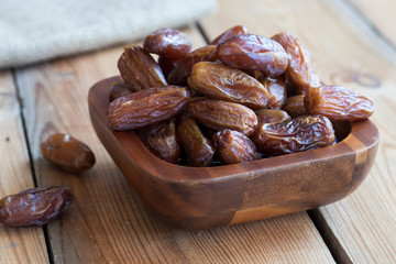 Dried dates in a bowl on a wooden table