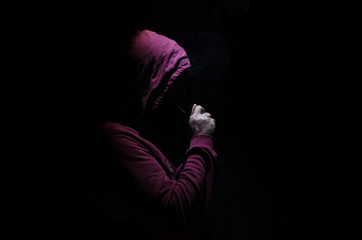 Vaping man holding a mod. A cloud of vapor. Black background. Vaping an electronic cigarette with a...