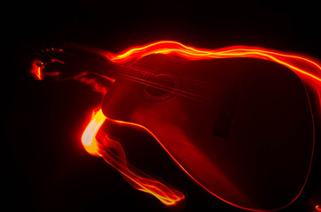 Music concept. Acoustic guitar isolated on a dark background under beam of light with smoke with copy space. Guitar Strings, close up. Selective focus. Fire effects