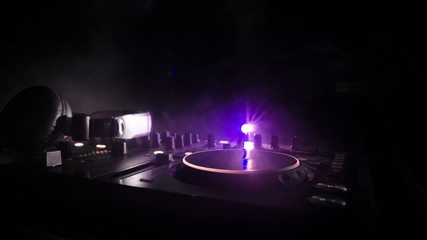 DJ Spinning, Mixing, and Scratching in a Night Club, Hands of dj tweak various track controls on dj's deck, strobe lights and fog, selective focus