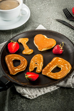 Celebrating Father's Day. Breakfast. The idea for a hearty and delicious breakfast: pancakes in form of congratulations - I love dad. In a frying pan, coffee mug and strawberries. copy space