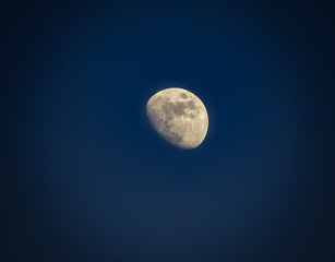Gibbous moon over dark blue sky seen with a telescope at night. Picture with vignetting.