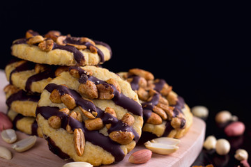 Cookies with peanuts covered with chocolate icing on a dark wooden background.