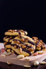 Cookies with peanuts covered with chocolate icing on a dark wooden background.