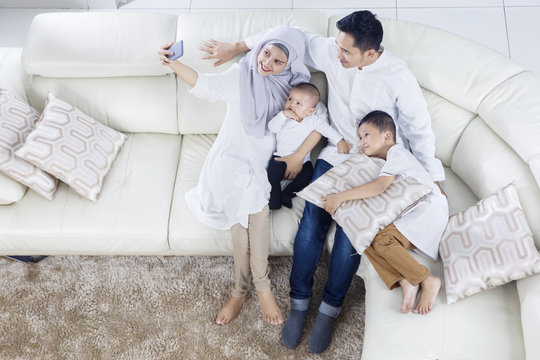 Muslim family taking selfie photo on sofa