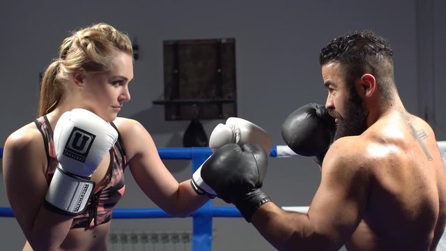 Beautiful girl engaged in boxing with trainer. Man and woman training in Boxing. Attractive woman talking to a trainer on a kickboxing in the ring