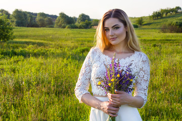 Naklejka na ściany i meble Young beautiful woman with flowers on meadow