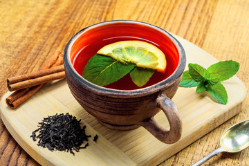 Mug of delicious hot black tea with fresh mint leaves and slice of lemon. Healthy drink made of black Ceylon tea, herbals and fruits.