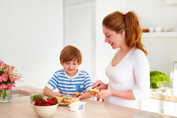 Obraz na płótnie Canvas happy mother and son preparing snacks in the morning at home kitchen