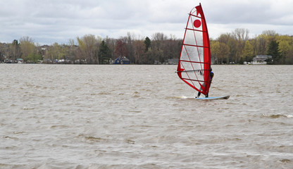 Man on lake windsurfing on a board with a mast 