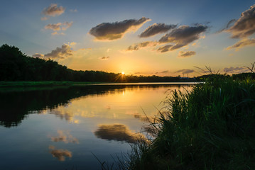 Naklejka na ściany i meble Sunset and clouds reflected in a lake