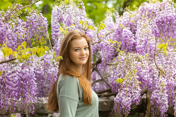 Natural beauty: red hair girl and freckles glow skin on the purple flowers background