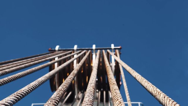 Timelapse metal cables of industrial crain structure outdoors under blue sky with white clouds on sunny day