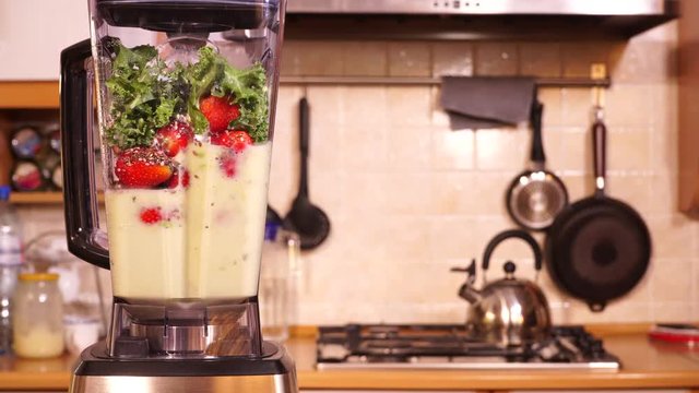Making fresh strawberry fruits shake milkshake with kale green leaves at home in blender high speed machine. Healthy eating, vegetarian food, diet concept. 4K ProRes HQ codec