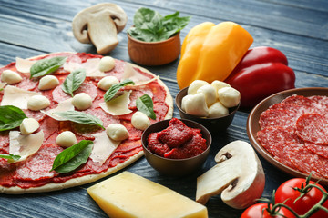Pizza with ingredients on wooden  background
