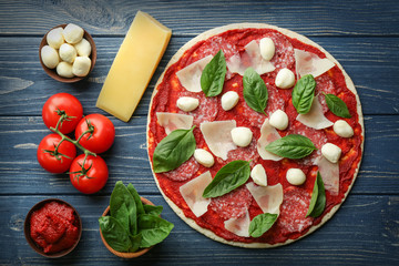 Pizza with ingredients on wooden  background