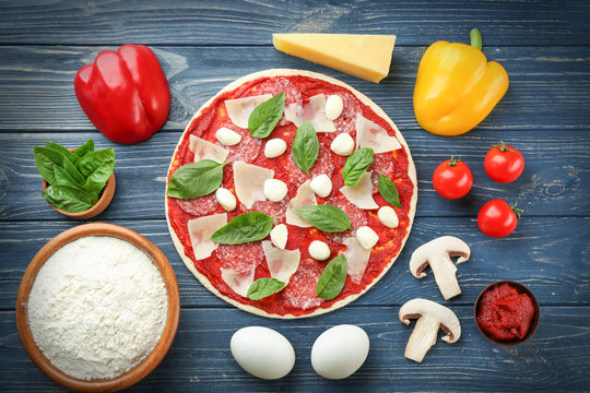 Pizza with ingredients on wooden  background