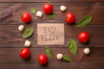 Paper with text I LOVE PIZZA and ingredients on wooden background