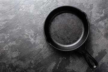Empty cast iron frying pan on dark grey culinary background, view from above © Sea Wave
