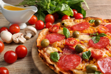 Tasty pizza with ingredients on wooden table
