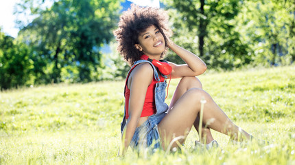 Naklejka na ściany i meble African american girl relaxing outdoor with headphones.