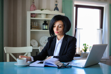 business lady dressed in black suit working on a laptop