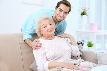Young man caring about grandmother at home