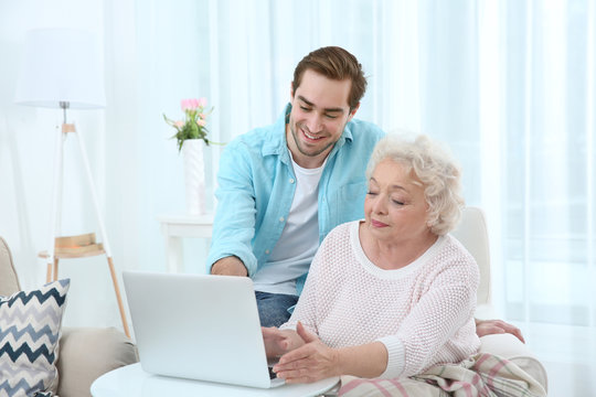 Young man caring about grandmother at home