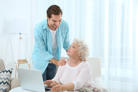 Young man caring about grandmother at home