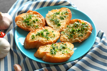 Tasty bread slices with grated cheese, garlic and herbs on plate