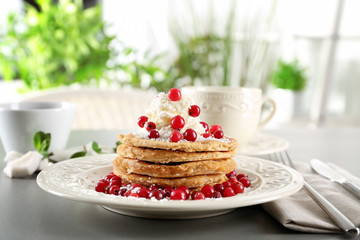 Stack of delicious coconut pancakes with butter cream, berries and shavings on table