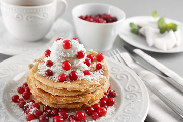Stack of delicious coconut pancakes with butter cream, berries and shavings on table
