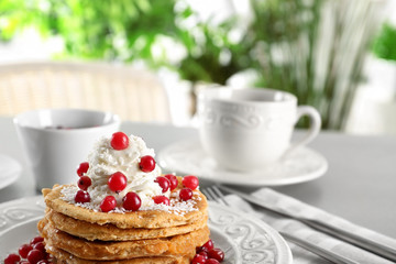 Stack of delicious coconut pancakes with butter cream, berries and shavings on table