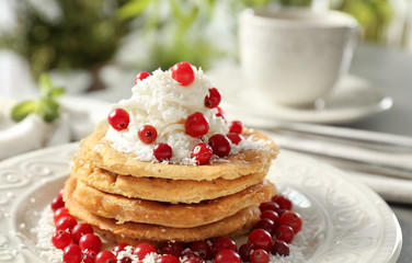Stack of delicious coconut pancakes with butter cream, berries and shavings on table