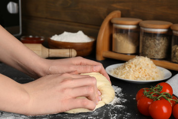 Female chef kneading dough for pizza on table