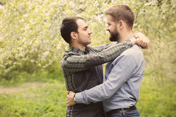 Happy gay couple hugging on blurred background