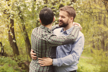 Obraz premium happy gay couple hugging in park