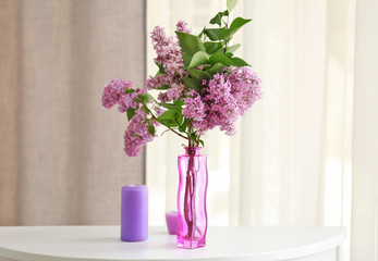 Glass vase with beautiful lilac flowers on wooden table