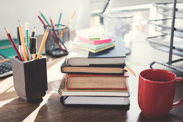 Stack of books and office supplies on wood table