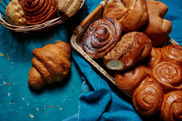 Top view sweet buns in a wooden woven basket and croissant closeup