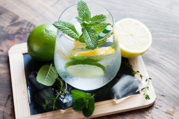 Refreshing cold iced mint drink with lemons and lime, summer drink with ice, selective focus, toned image