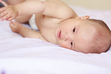 A baby is lying on a white sheet