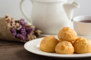 Homemade cream puffs filled vanilla custard cream or choux cream custard on wood table serve with tea in white pot or cup of coffee. Cream puffs,eclair, choux or puff pastry is french dessert.