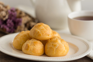 Homemade cream puffs filled vanilla custard cream or choux cream custard on wood table serve with tea in white pot or cup of coffee. Cream puffs,eclair, choux or puff pastry is french dessert.